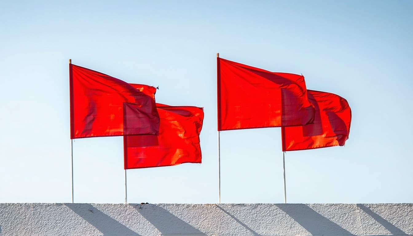 Four red flags against a sunny sky